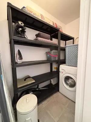 a laundry room with black shelves next to a washing machine at Appartement T2 Vieux Port d'Ajaccio in Ajaccio