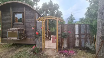 a small house with an open door and a gate at La roulotte au coeur du maquis in Carbuccia