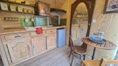 a kitchen with wooden cabinets and a small table at La roulotte au coeur du maquis in Carbuccia