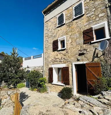 a stone house with wooden doors and windows at Belle maison de montagne proche Ajaccio in Bastelica