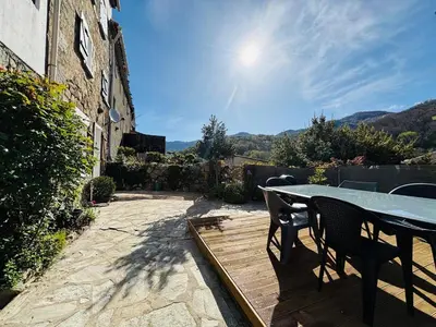 a table and chairs on a patio with the sun at Belle maison de montagne proche Ajaccio in Bastelica