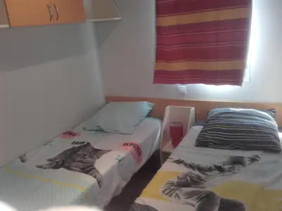 two beds in a small room with a window at Mobil-Home dans lotissement très tranquille in Vescovato