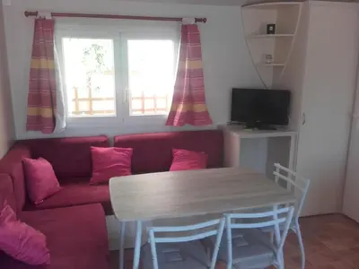 a living room with a red couch and a table at Mobil-Home dans lotissement très tranquille in Vescovato