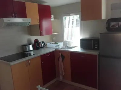 a kitchen with red cabinets and a sink and a refrigerator at Mobil-Home dans lotissement très tranquille in Vescovato