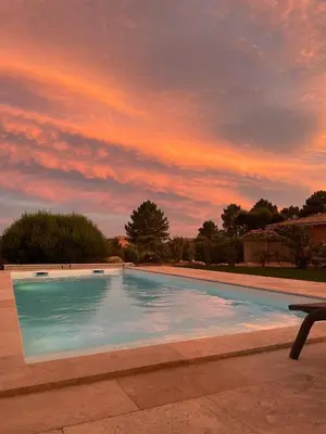 a large swimming pool with a sunset in the background at Villa Chez Géraldine Piscine chauffée, proche plage et rivière in Lecci