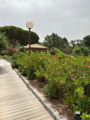 a wooden walkway with flowers in front of a building at Les Jardins De Santa Giulia - Charmante chambre dhte 2 in Porto-Vecchio