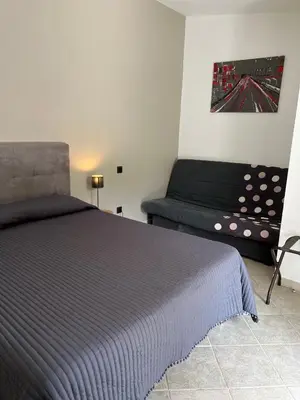 a bedroom with a bed and a futon in it at Les Jardins De Santa Giulia - Charmante chambre dhte 2 in Porto-Vecchio