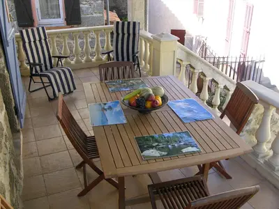 a wooden table with a bowl of fruit on a balcony at Maison Le Rêve in Evisa