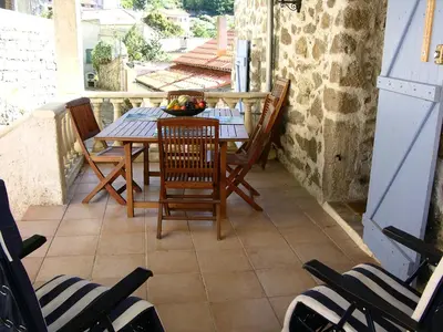 a table and chairs on the balcony of a house at Maison Le Rêve in Evisa