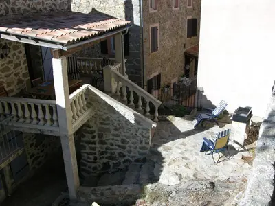 a building with a porch and a staircase and chairs at Maison Le Rêve in Evisa