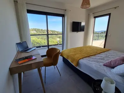 a bedroom with a bed and a desk with a laptop on it at Villa Mekasteni in Cirendinu