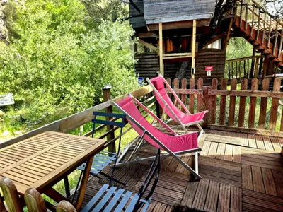 two chairs and a table on the deck of a cabin at GITES O FIL DE L'EAU piscine spa accès rivière in Omessa