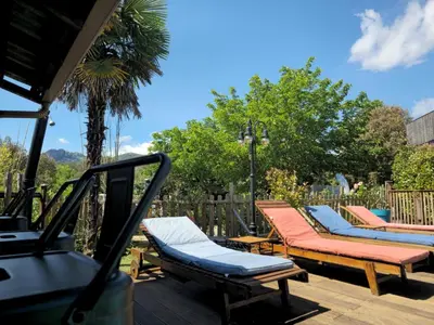 a row of chaise lounges and chairs on a deck at GITES O FIL DE L'EAU piscine spa accès rivière in Omessa