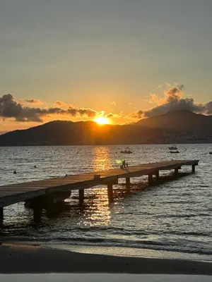 a sunset over the ocean with a wooden pier at Superbe appartement neuf de haut standing in Ajaccio