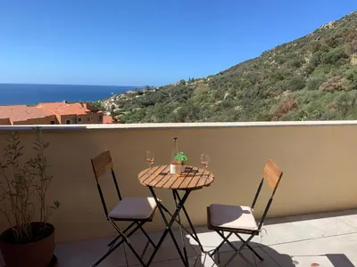 a table with two chairs and wine glasses on a balcony at Superbe appartement neuf de haut standing in Ajaccio
