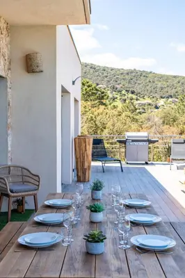 a wooden table with wine glasses and plants on a patio at Villa Tinoeva Mare di Conca in Conca