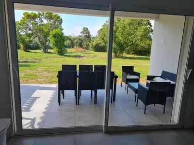 a dining room with a table and chairs through a sliding glass door at Location 