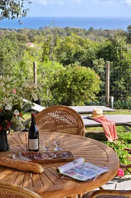 a wooden table with a bottle of wine on top of it at Domaine Punta della Guardia villa panorama maquis et mer, plage à 1,5 Km in Cervione