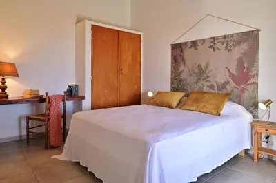 a bedroom with a white bed with a wooden cabinet at Domaine Punta della Guardia villa panorama maquis et mer, plage à 1,5 Km in Cervione
