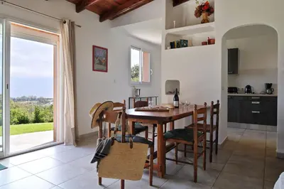 a kitchen and dining room with a wooden table and chairs at Domaine Punta della Guardia villa panorama maquis et mer, plage à 1,5 Km in Cervione
