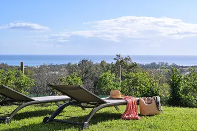 two chairs sitting in the grass with a hat and a purse at Domaine Punta della Guardia villa panorama maquis et mer, plage à 1,5 Km in Cervione