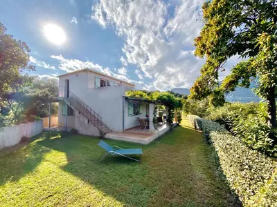 a yard with a white house with a blue chair at Domaine Punta della Guardia villa vue mer dans nature protégée, plage à 1,5 km in Cervione