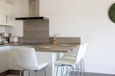 a kitchen with a counter with white bar stools at Résidence Domaine d'Arca Porto Vecchio - T2 haut standing - 4 personnes 