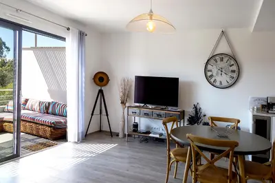 a living room with a table and a clock on the wall at Domaine d'Arca - Aragon 11 - 4 pers - « Au jardin d'Arca » in Porto-Vecchio