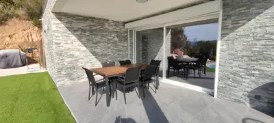 a dining room with a table and chairs on a patio at F4 à Porticcio avec piscine et vue sur mer in Porticcio