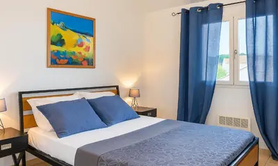 a bedroom with a bed with blue curtains and a window at Locations 