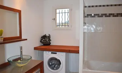 a bathroom with a washing machine and a sink at Locations 