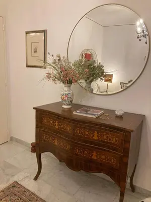 a dressing table with a mirror and a vase with flowers on it at AJACCIO VUE MER, 3 chambres, 6 personnes in Ajaccio