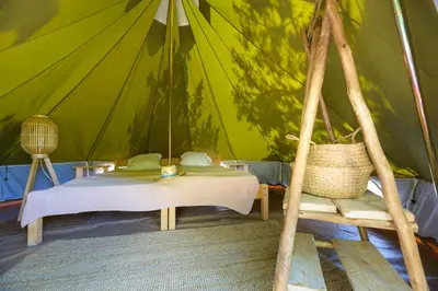 a bedroom in a tent with a bed and a chair at Camping U Pirellu in Porto-Vecchio