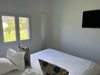a white bedroom with a bed and a window at Les Bergeries in Ajaccio