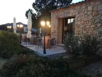 a patio with a table with chairs and an umbrella at Les Bergeries in Ajaccio