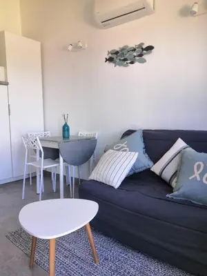 a living room with a blue couch and a table at Porticcio très joli T2 climatisé & grande terrasse à 1km de la plage in Porticcio