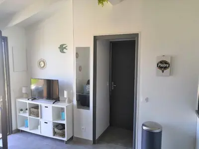 a room with a door and a tv and a shelf at Porticcio très joli T2 climatisé & grande terrasse à 1km de la plage in Porticcio