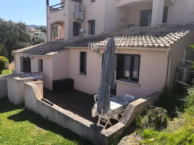 a house with an umbrella and a chair on a deck at Porticcio très joli T2 climatisé & grande terrasse à 1km de la plage in Porticcio