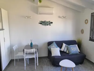 a living room with a blue couch and a table at Porticcio très joli T2 climatisé & grande terrasse à 1km de la plage in Porticcio