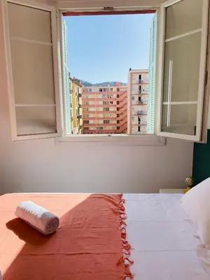 a bed in a room with a large window at Appartement Bonaparte centre ville d'Ajaccio in Ajaccio