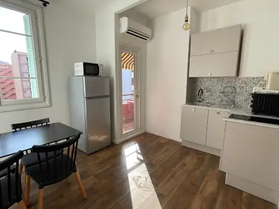 a kitchen with a table and a refrigerator at Appartement Bonaparte centre ville d'Ajaccio in Ajaccio
