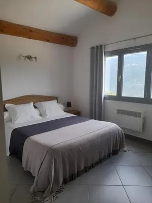 a bedroom with a large bed and a large window at Chambres d'Hôtes Villa Cardellini in Aullène