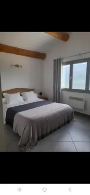 a bedroom with a large bed and a large window at Chambres d'Hôtes Villa Cardellini in Aullène