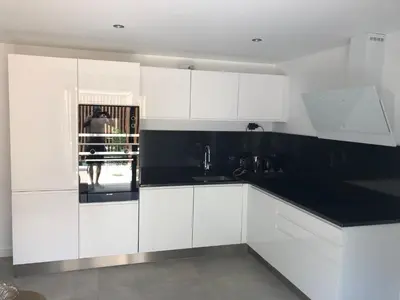 a kitchen with white cabinets and a black counter top at La Verda in Bonifacio