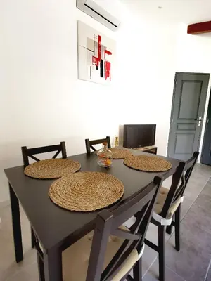 a dining room table with four chairs and a table with plates and bowls at Indè Noi - Maison de village proche commodités in Murato