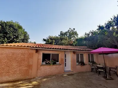 a small house with a table and an umbrella at Indè Noi - Maison de village proche commodités in Murato