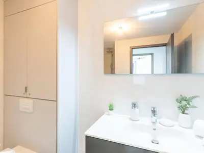 a white bathroom with a sink and a mirror at Apartment Stanatura-5 by Interhome in Porto-Vecchio