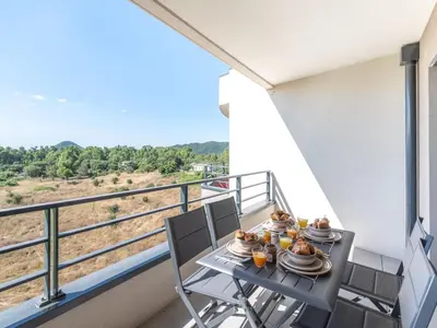 a balcony with a table with plates of food on it at Apartment Stanatura-5 by Interhome in Porto-Vecchio