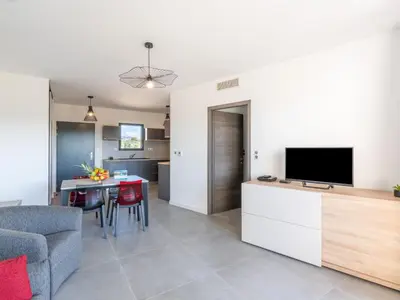 a living room with a television and a table with chairs at Apartment Stanatura-5 by Interhome in Porto-Vecchio