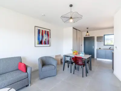 a living room with a couch and a table and chairs at Apartment Stanatura-5 by Interhome in Porto-Vecchio